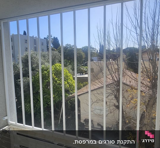 סורגים מותקנים על מרפסת עם נוף לעצים ובניינים